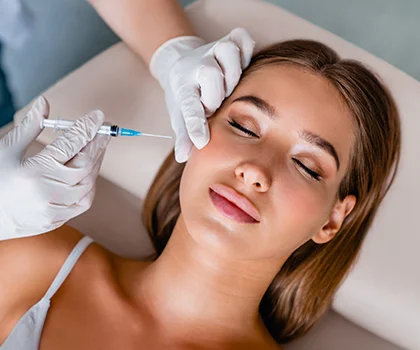 blonde woman peacefully laying on patient bed with a Doctor injecting fillers in her cheek - Dermal Fillers in San Francisco, CA