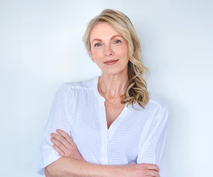 Blonde woman in white shirt, arms crossed with content and peaceful expression - Neck Lift procedure in San Francisco, CA