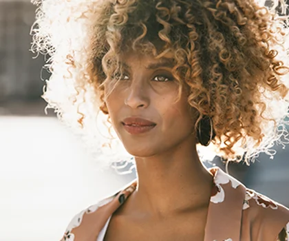 Content woman with blonde afro, in an urban setting - Scar Revision in San Francisco, CA